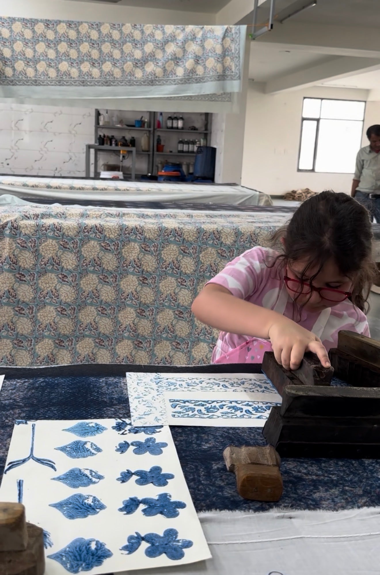A mother shows her son how to choose a block among printed pattern sheets on the studio table