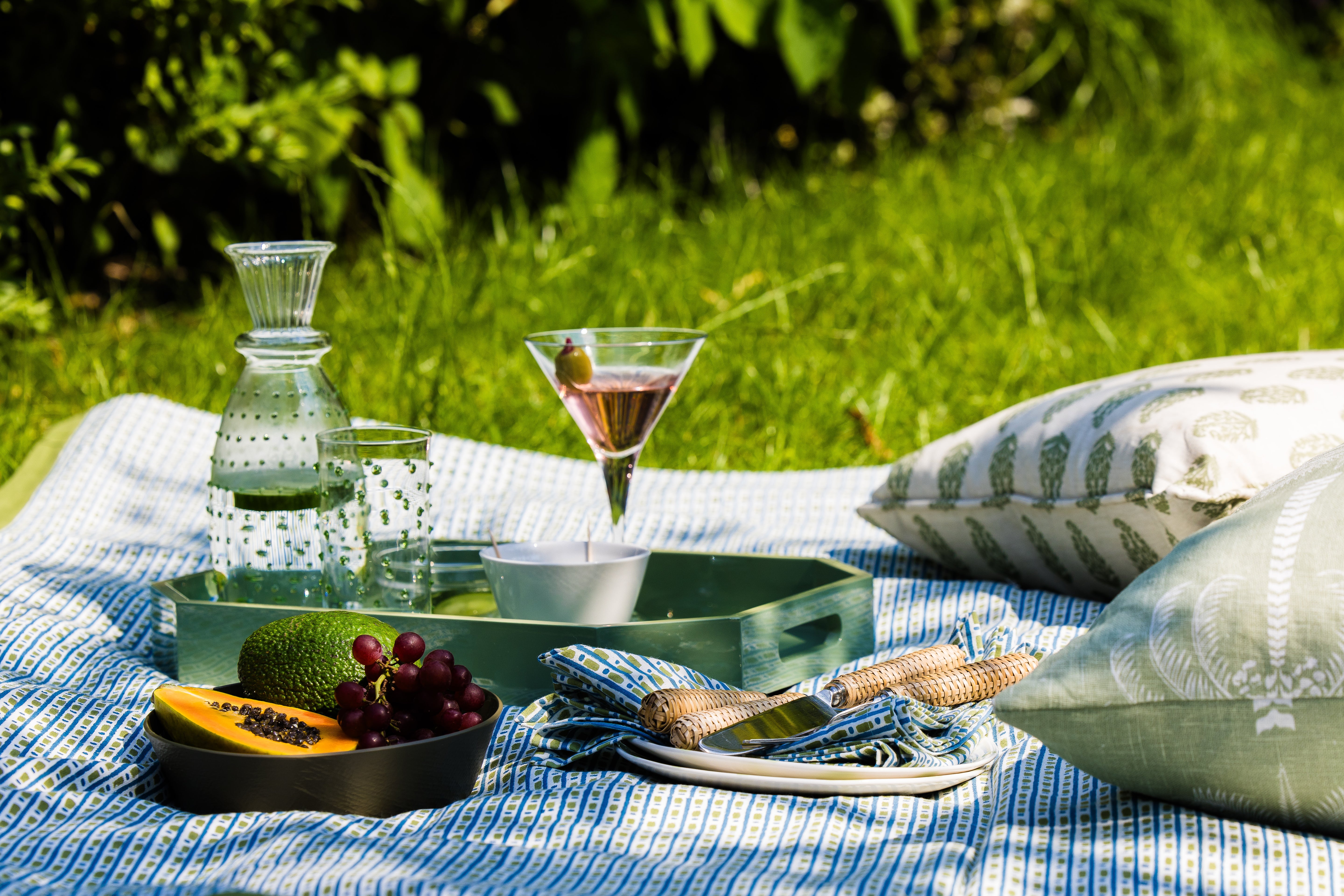 Outdoor picnic setup with drinks, fruits, and snacks on a Contemporary Green and Turquoise Cotton Tablecloth with matching napkins.