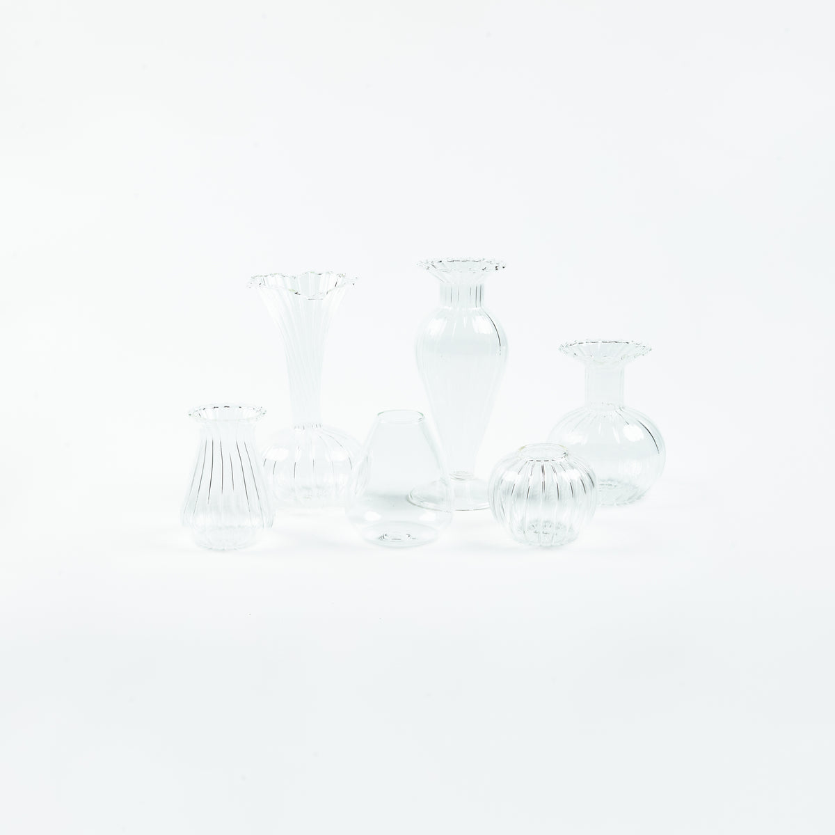 Six clear ribbed glass bud vases in assorted shapes with frilled rims, by Rosie Dalia