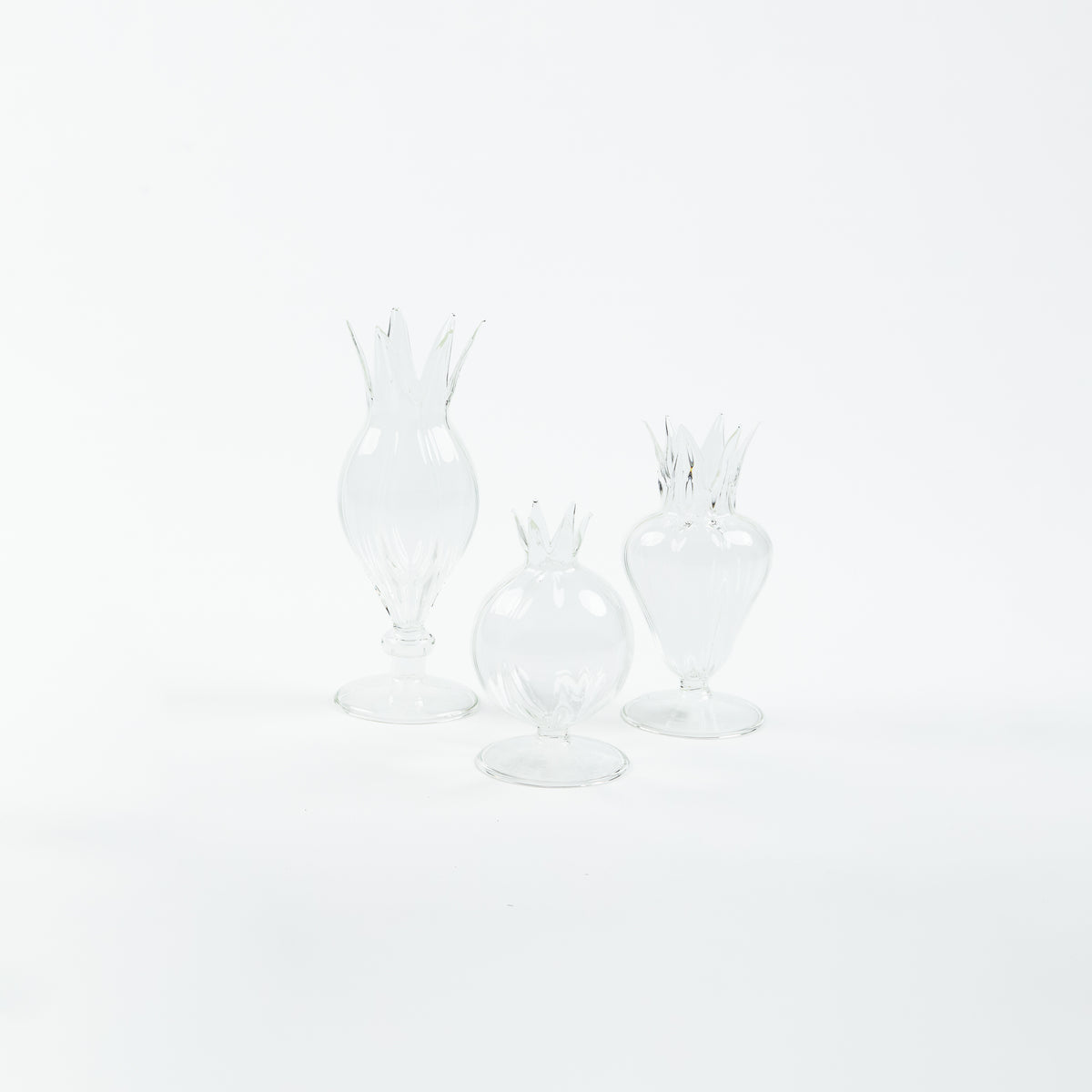 Three clear glass pomegranate-shaped bud vases with crown tops and footed bases, by Rosie Dalia