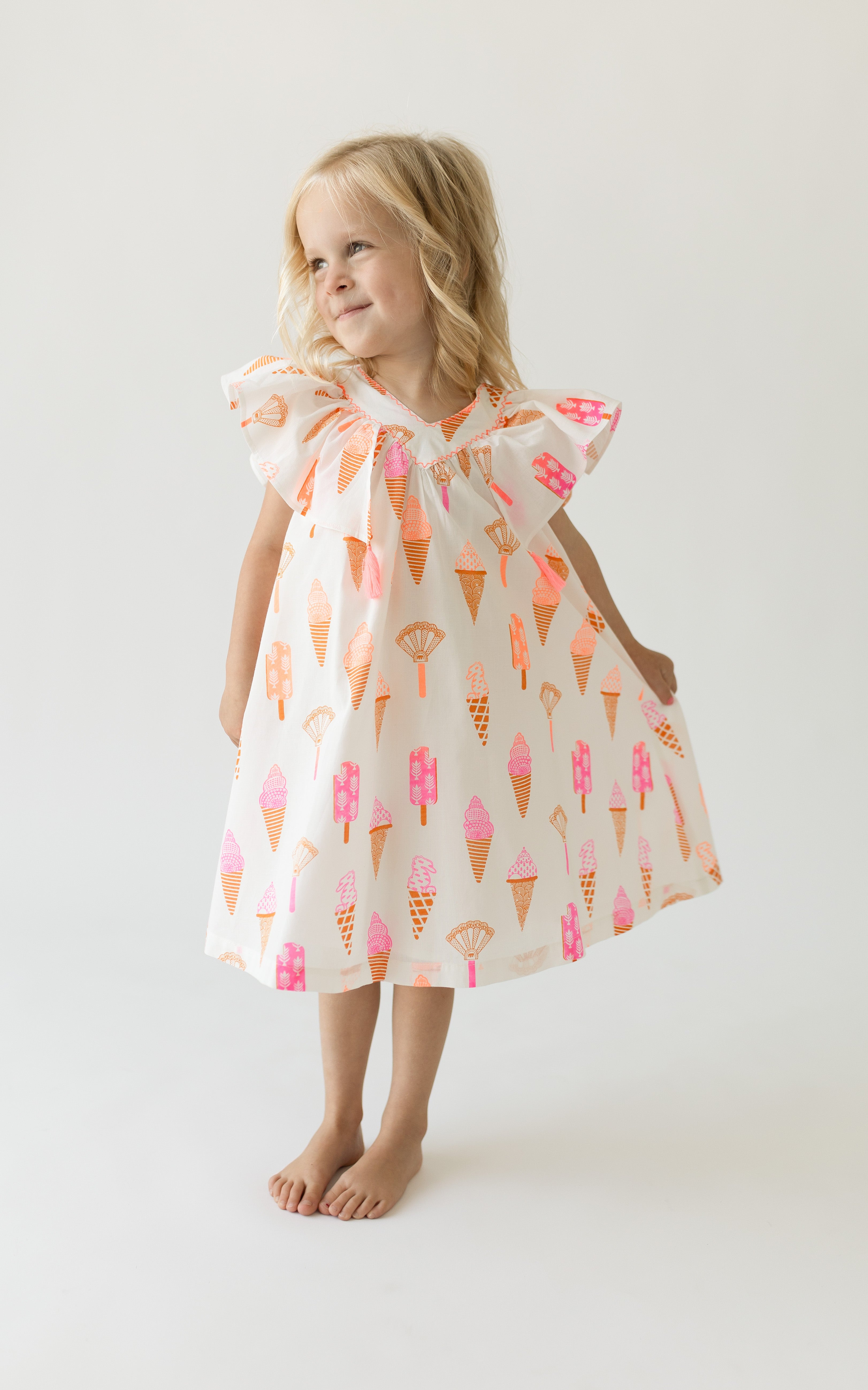 A girl wearing a short-sleeved cotton dress with an ice cream print.