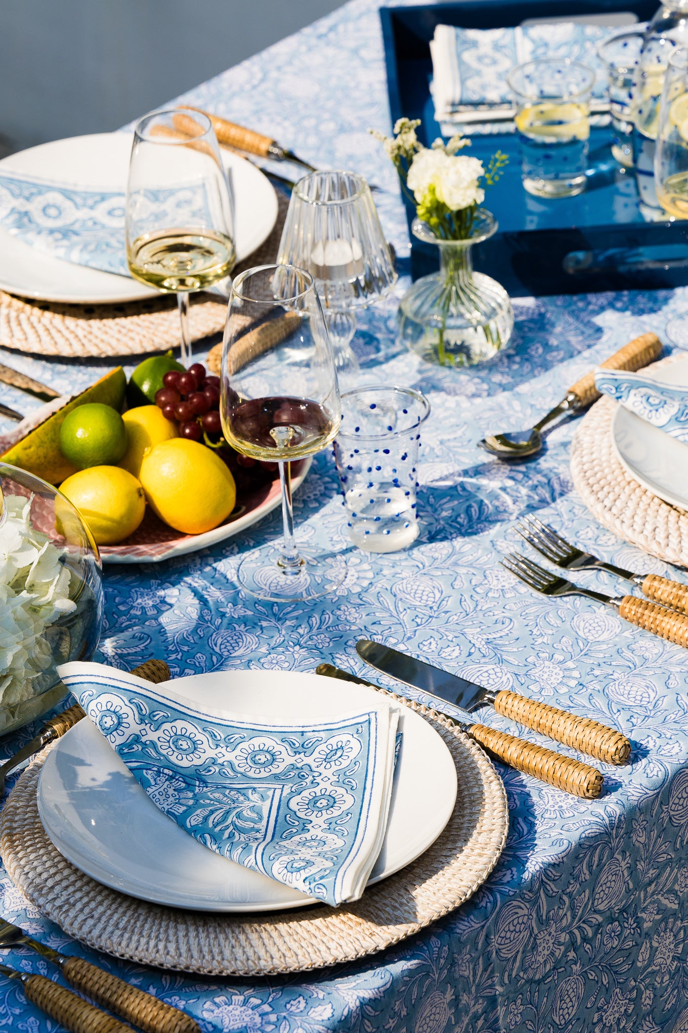 Elegant table setting with blue and white tablecloth, plates, glasses, and silverware.